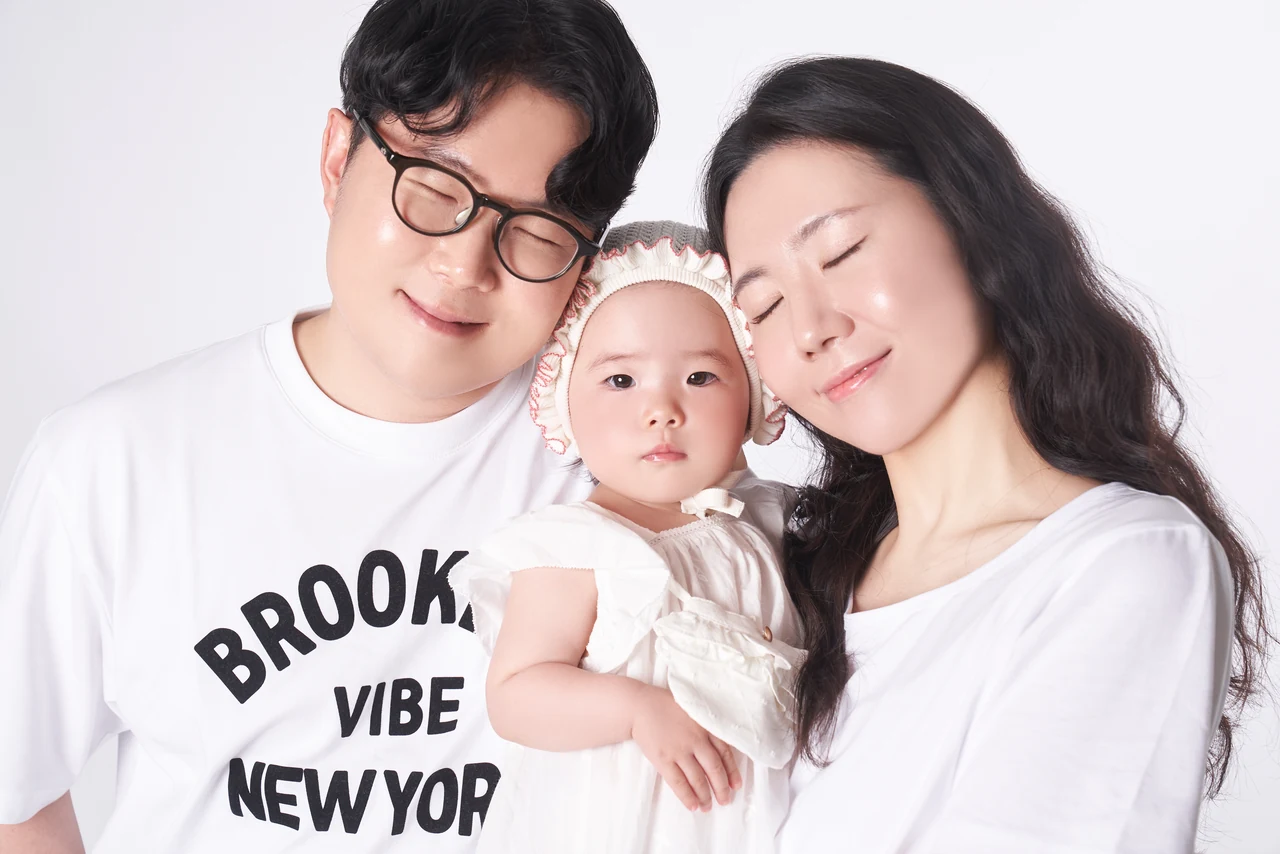 아기를 사이에 두고 이마를 맞댄 세 가족의 사진